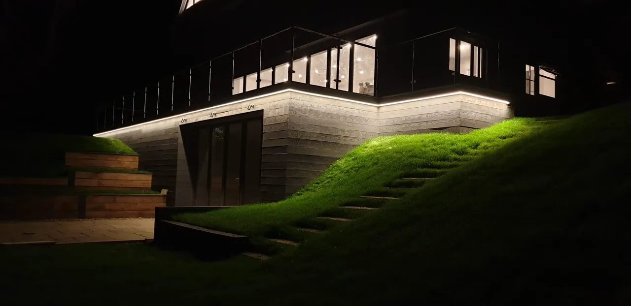 Home exterior at night with garden and security lighting